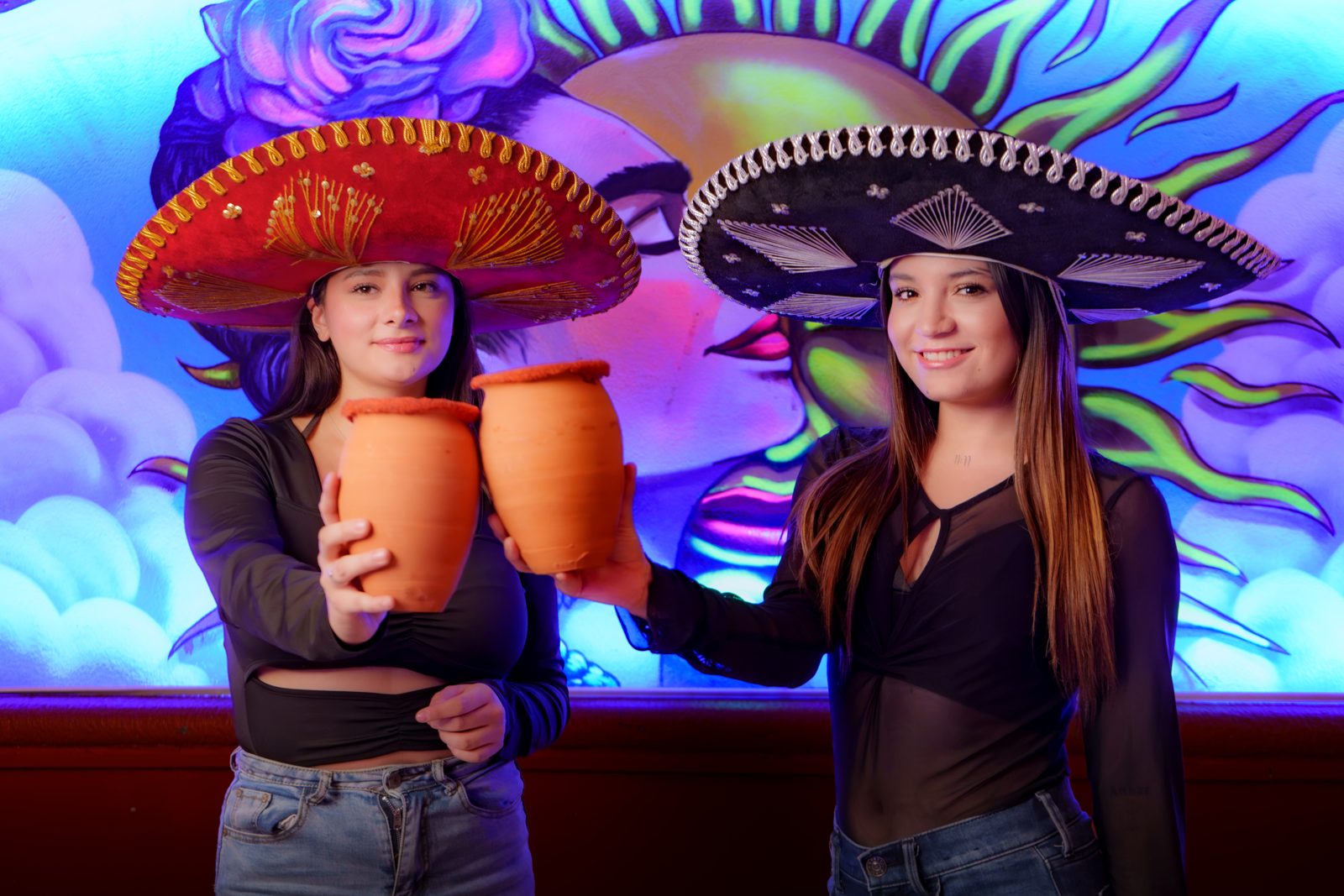 Amigas brindando con cantaritos y sombreros de charro