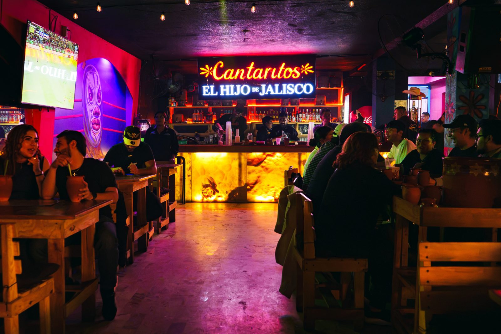 La barra del segundo piso llena, con neón y pantallas