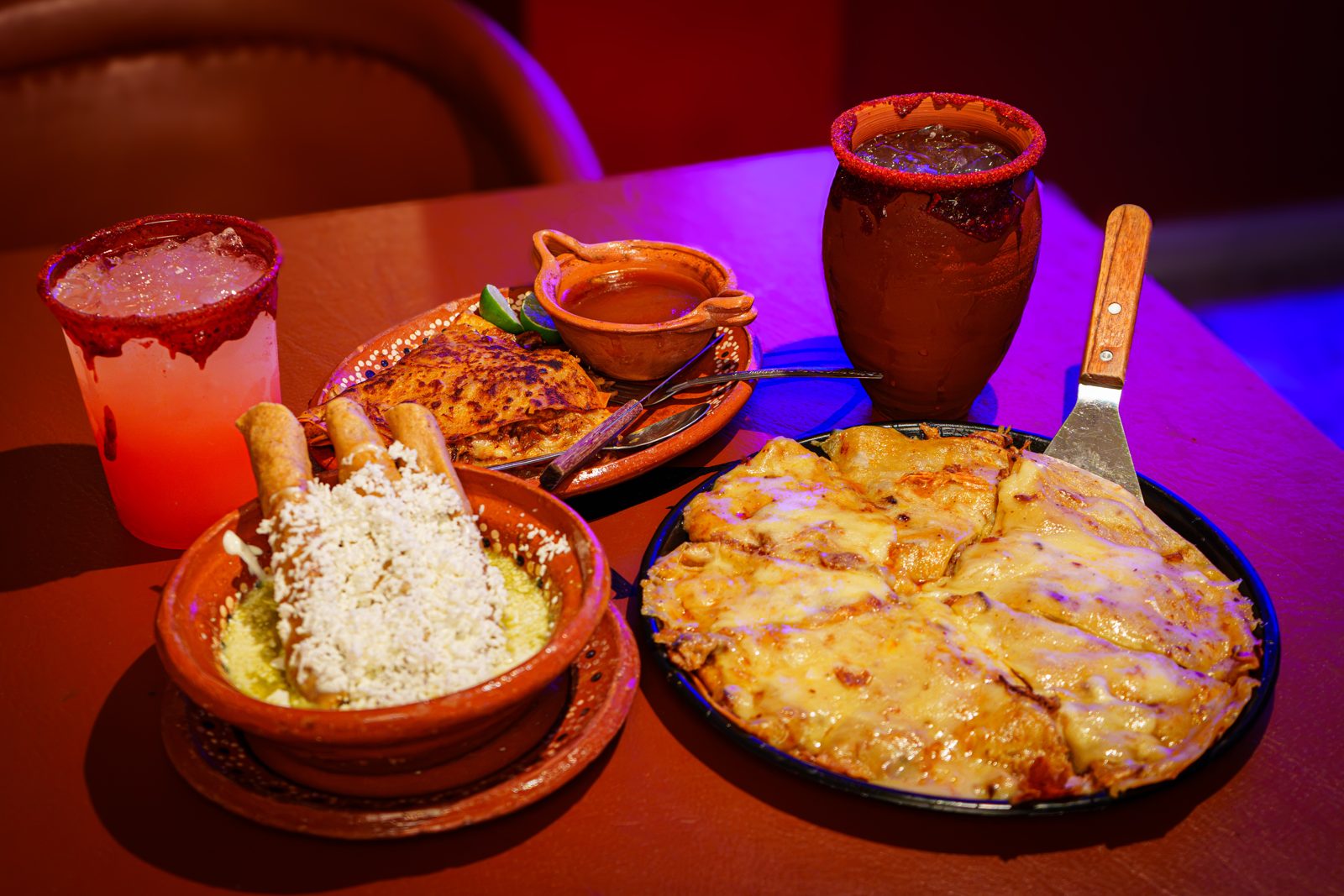 Mesa con pizzabirria, guacamole y cantaritos