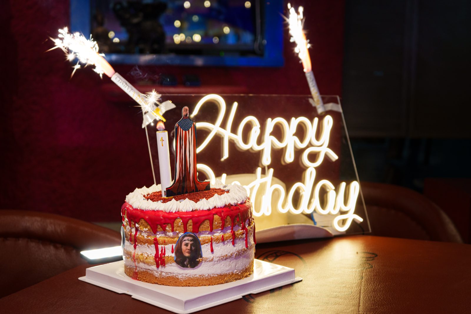 Pastel de cumpleaños con bengalas y letrero neón de Happy Birthday
